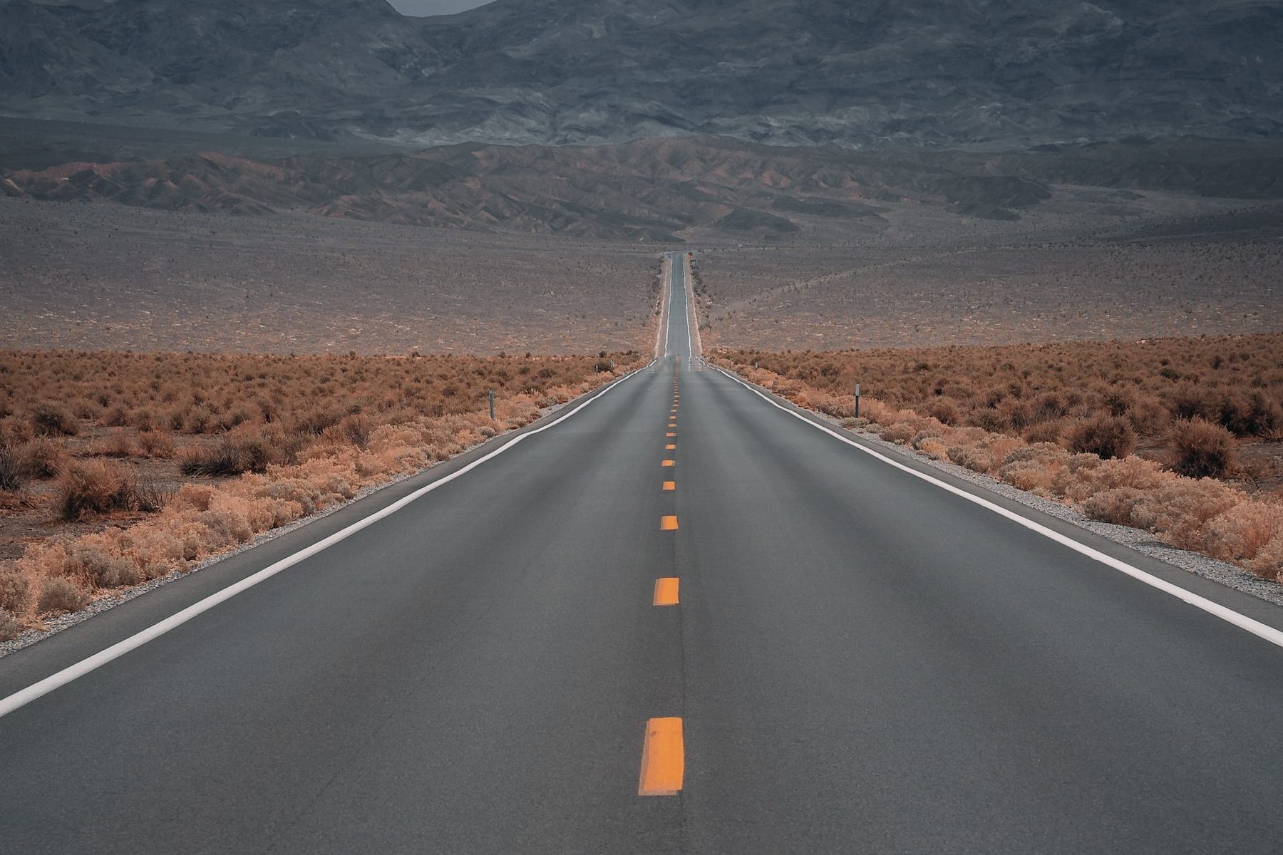 black asphalt road in the middle of brown field during daytime